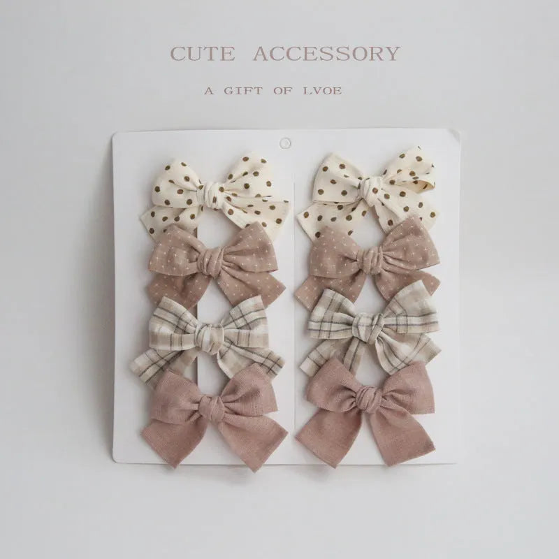 Set of eight cloth hairclips for children with dovetail bow designs in various colour patterns.
