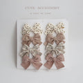 Set of eight cloth hairclips for children with dovetail bow designs in various colour patterns.