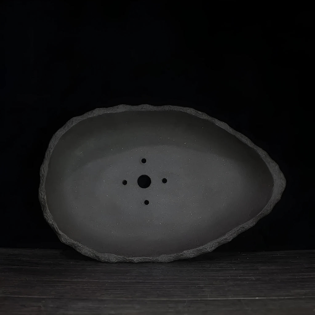 Handmade purple clay flower pot with unique sculpted shape for floor-standing plants.