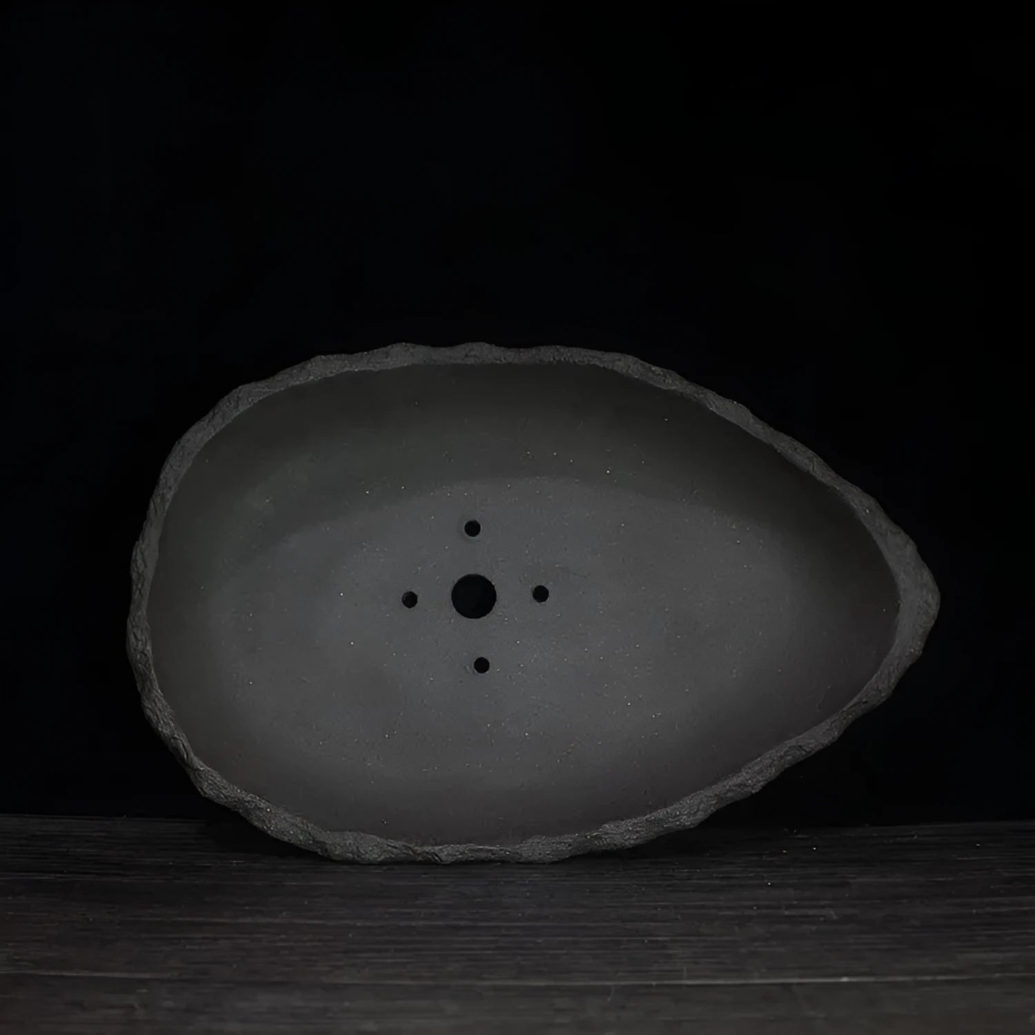 Handmade purple clay flower pot with unique sculpted shape for floor-standing plants.