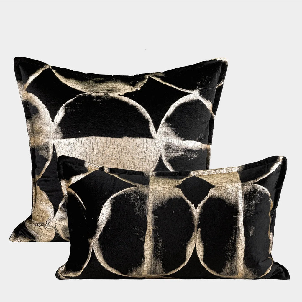 Black and gold abstract pattern flannel pillow cover on a grey sofa.