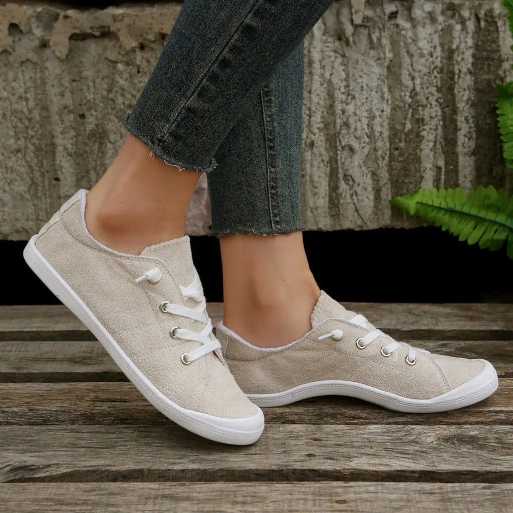 Creamy-white low-top fabric sneaker for women with a rubber sole on a neutral background