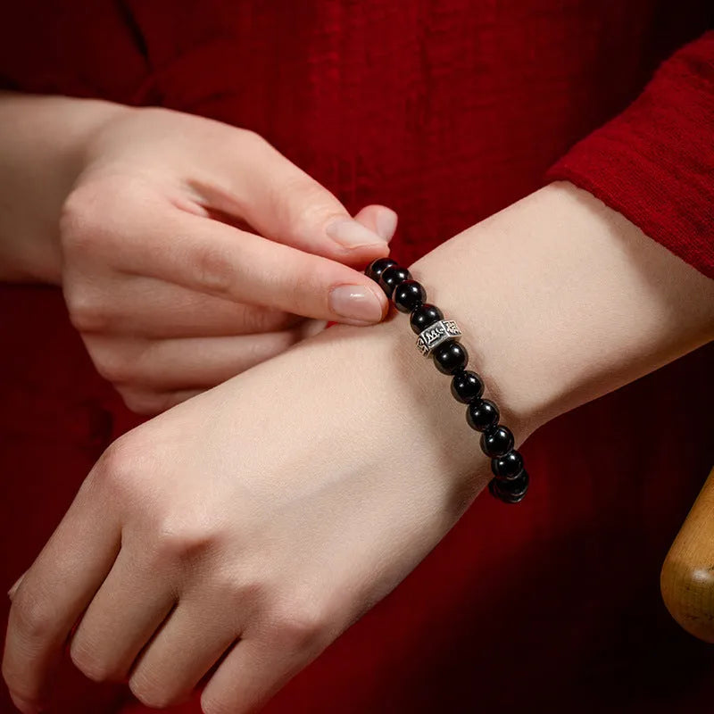 Close-up of an 8mm obsidian beaded bracelet with zodiac and Buddhist bodhisattva designs.