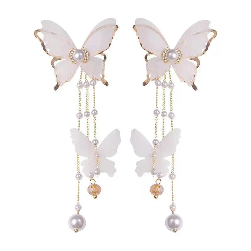 White butterfly earrings with lace detailing, tassels, and rhinestone accents on copper alloy