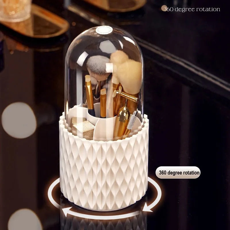 White acrylic rotating makeup brush holder with transparent body and a grey dust cover on a desk.