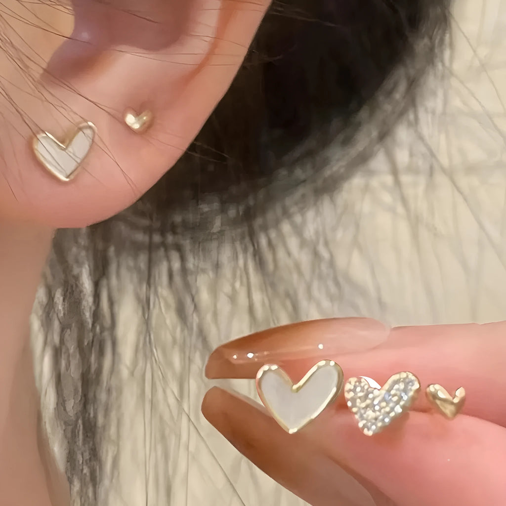 Set of three pairs of heart-shaped alloy earrings in gold, black, black and white, and pink colours.