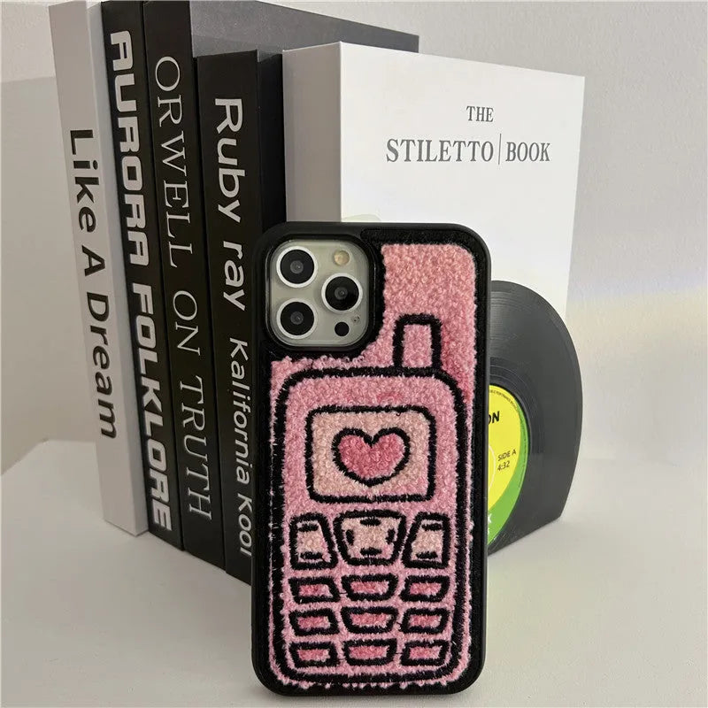 Pink towel embroidered soft TPU back cover case for iPhone models on a table.