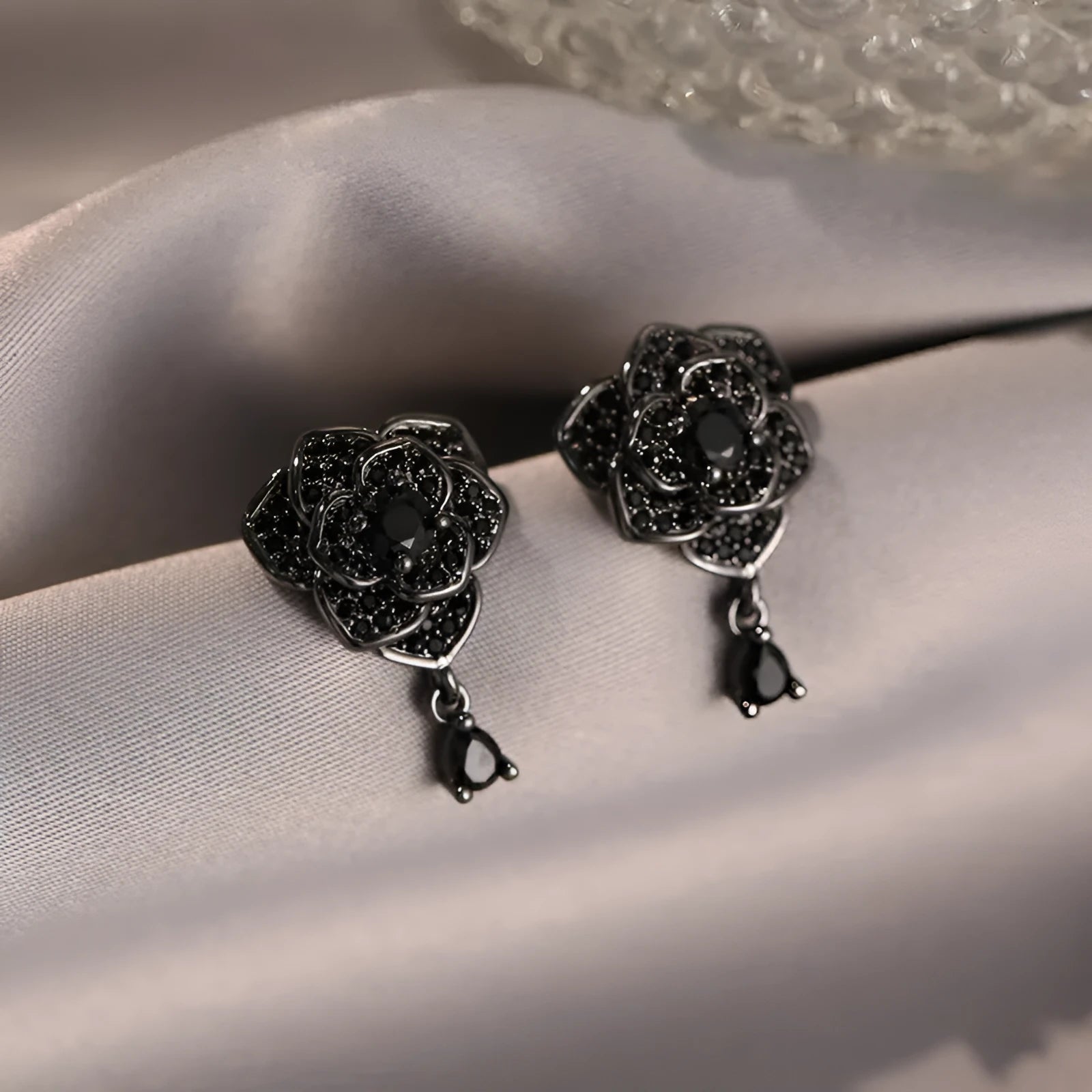 A pair of black rose zircon floral stud earrings with an 18K gold electroplated finish on copper.