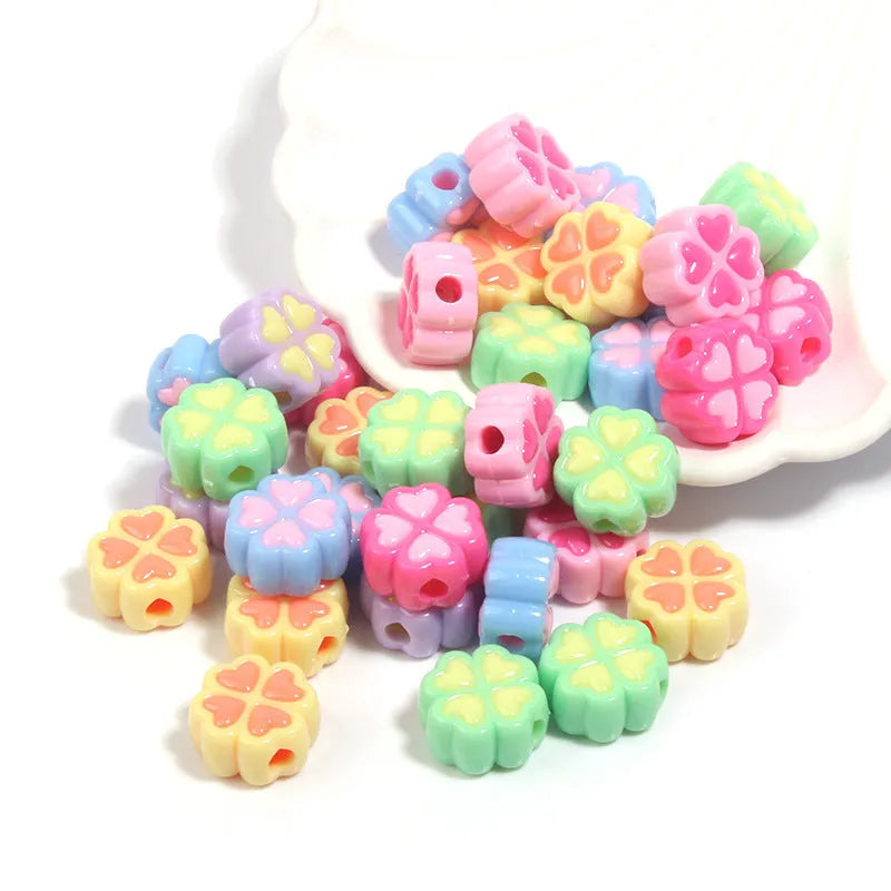 A selection of 15mm frosted acrylic beads in various colours, each showing a four-leaf clover love pattern.