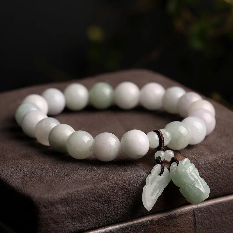Apple green jade bracelet with carved Maitreya Buddha, gourd, and money bag beads.