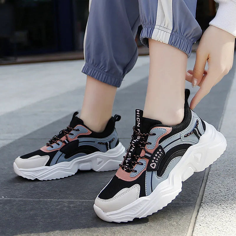 Women's white thick-soled casual sneakers with mesh upper, round toe, and buckle detail.