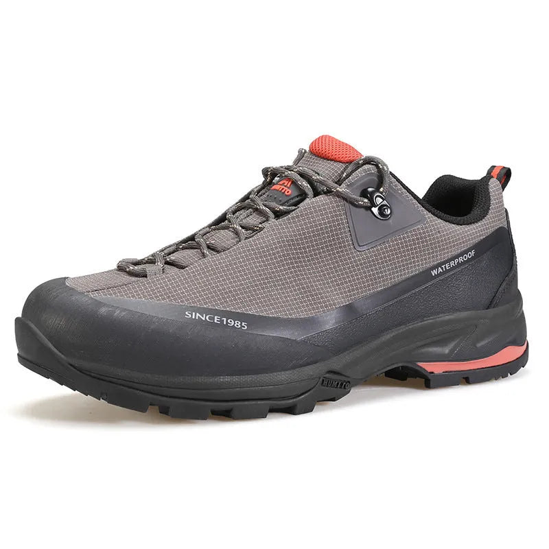Men's low-top hiking boots in dark grey with round toe and front lace-up design on a rocky trail.