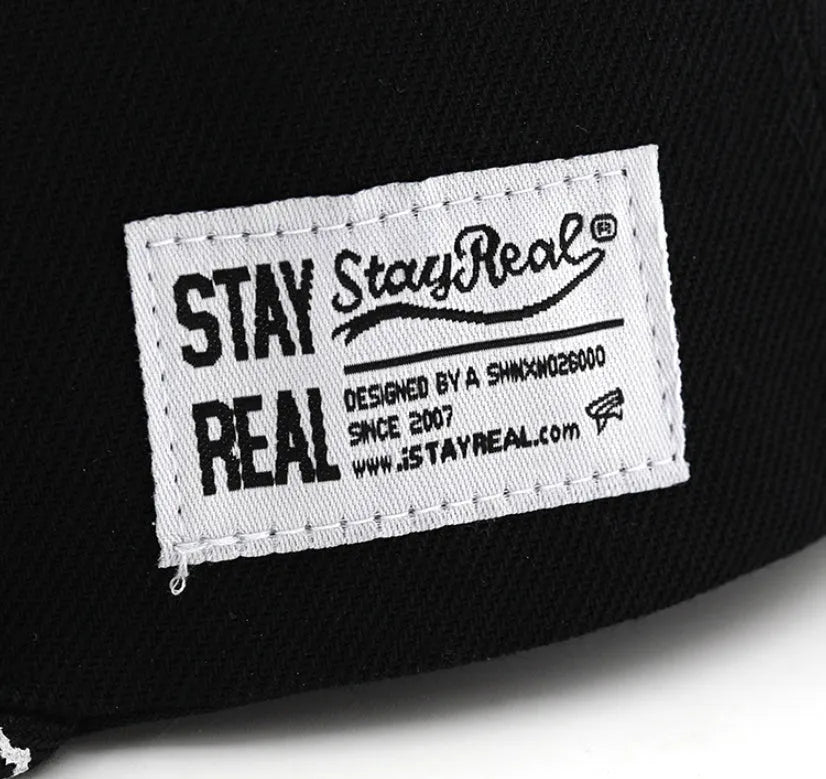 Black and white cotton baseball cap with letter embroidery on the front, showing adjustable strap.