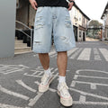 Light blue ripped denim shorts with distressed detailing and loose straight leg fit on a mannequin.