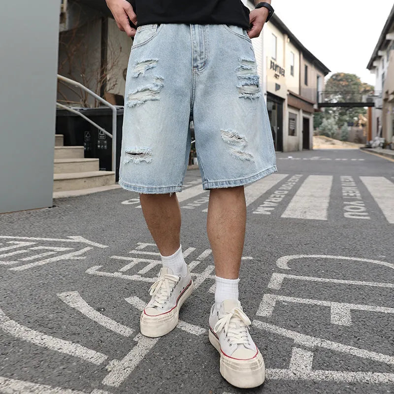 Light blue ripped denim shorts with distressed detailing and loose straight leg fit on a mannequin.