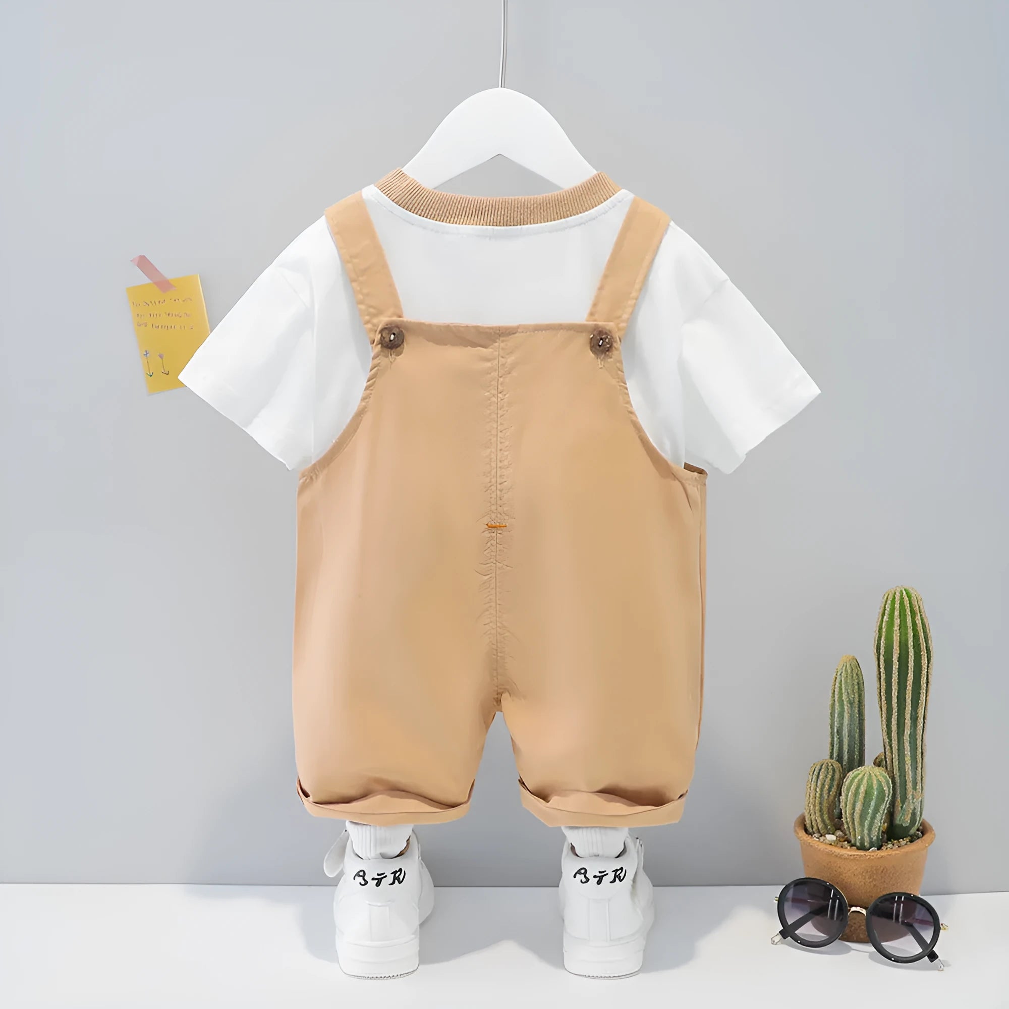 Yellow baby short-sleeved cotton overalls with cartoon print, adjustable straps, and an openable front.