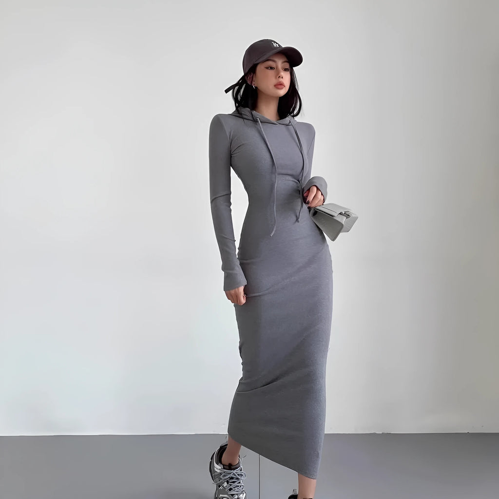 A woman wearing a grey hooded sheath dress with long sleeves and an over-the-knee length.