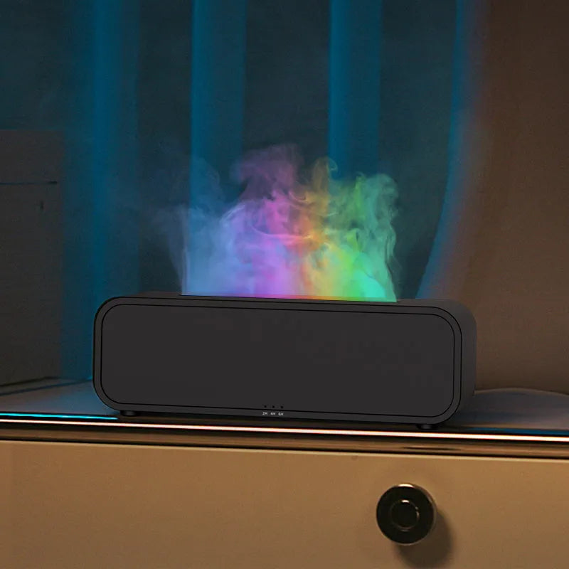 Black and white aroma diffuser with remote control on a table, showing colour-changing LED lights.