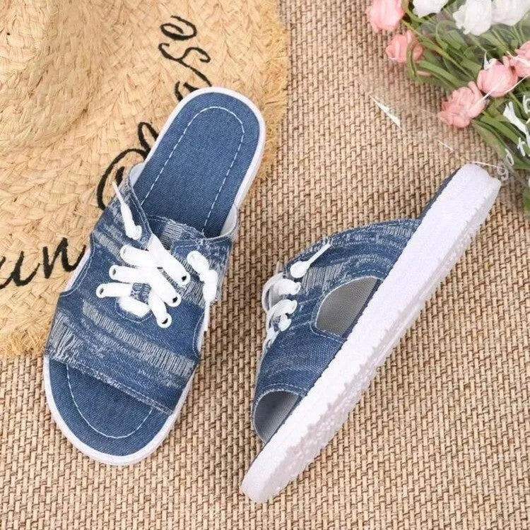 Blue women's Roman-style flat canvas slippers with a rubber sole, shown from the side.