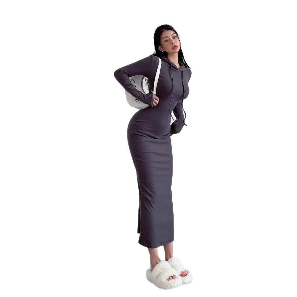 A woman wearing a grey hooded sheath dress with long sleeves and an over-the-knee length.