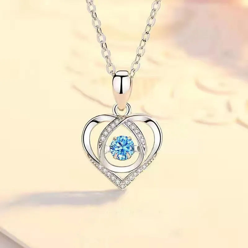 Geometric heart pendant necklace with mixed gem inlays and matching bracelet on blue background