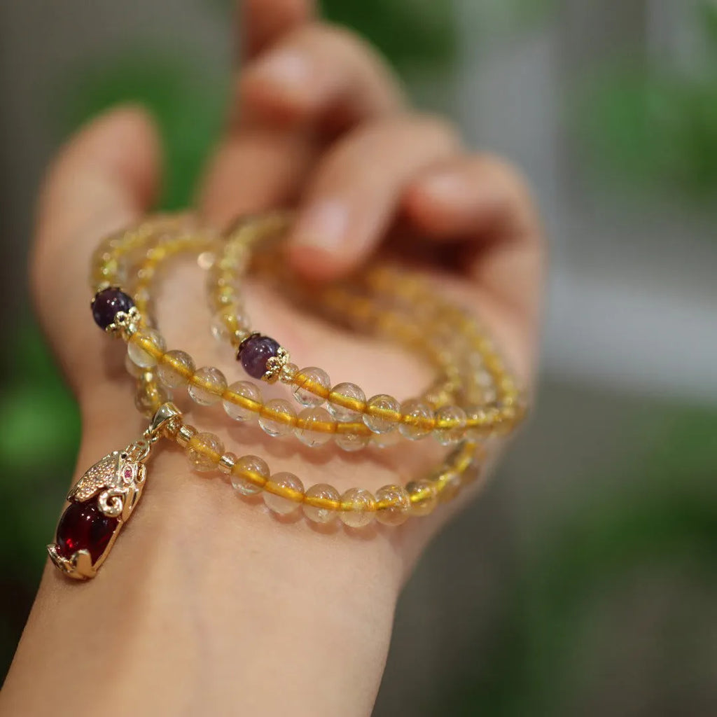 Natural gold rutilated quartz bracelet with three gold rings on wrist
