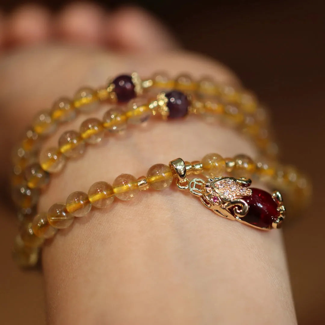 Natural gold rutilated quartz bracelet with three gold rings on wrist