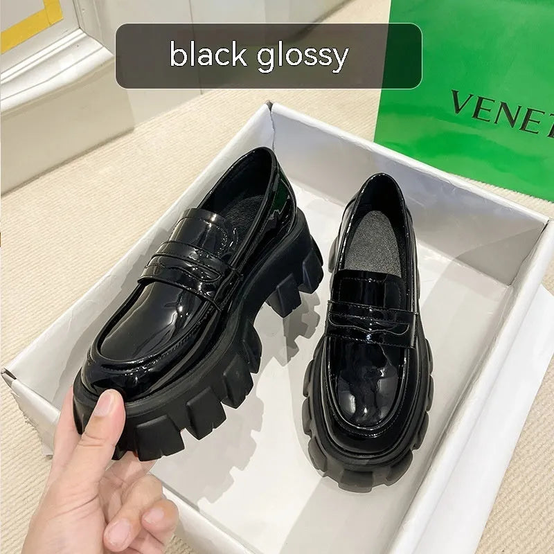 A pair of wide fit patent leather loafers with a rubber sole and muffin heel base.