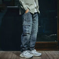 Man wearing blue loose straight-leg denim trousers with a zip fly, showcasing a casual retro style.