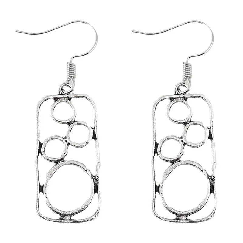 A pair of antique silver geometric earrings showing an irregular square shape inside a round ring.