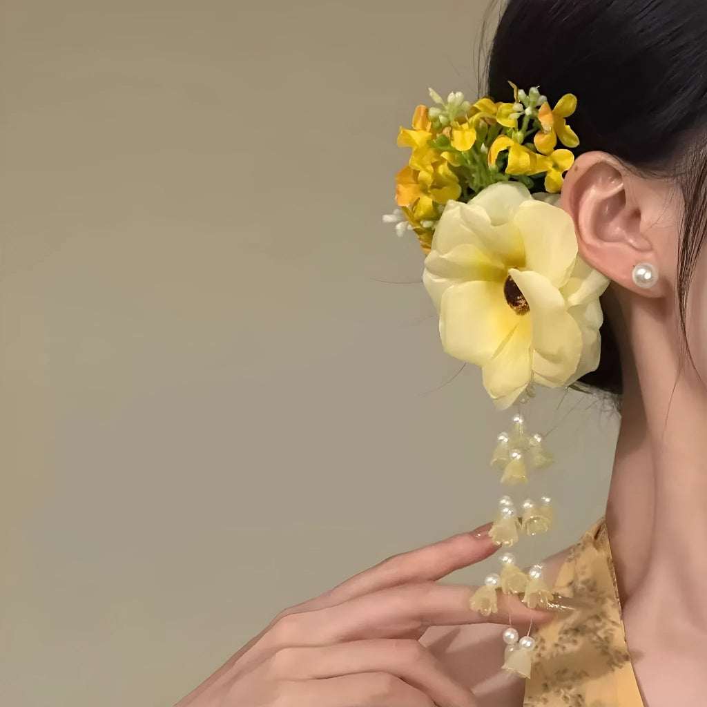 Yellow flower tassel side clip hair accessory on a white background.