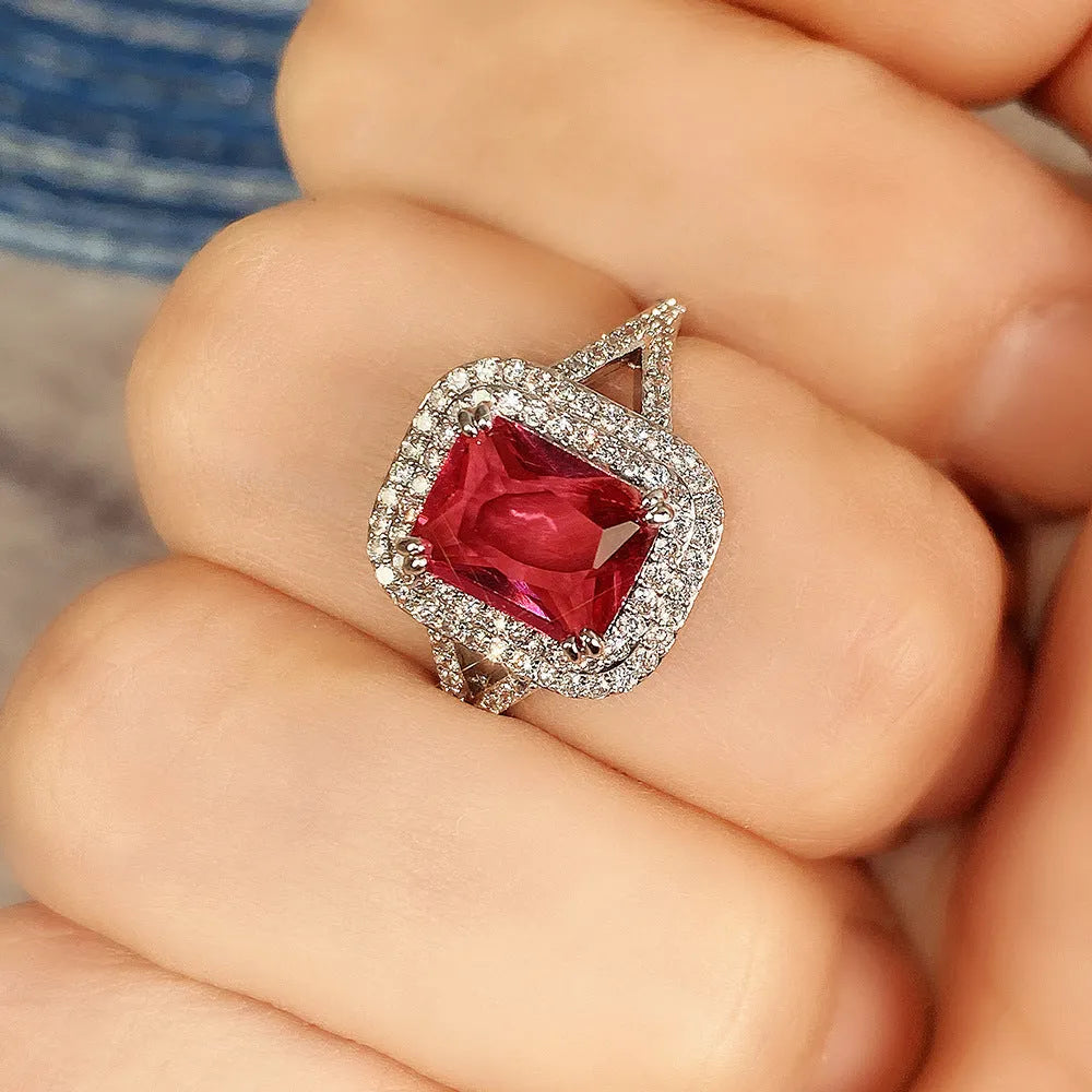 Copper square ring with red rhinestones on a woman's hand, showing geometric design.