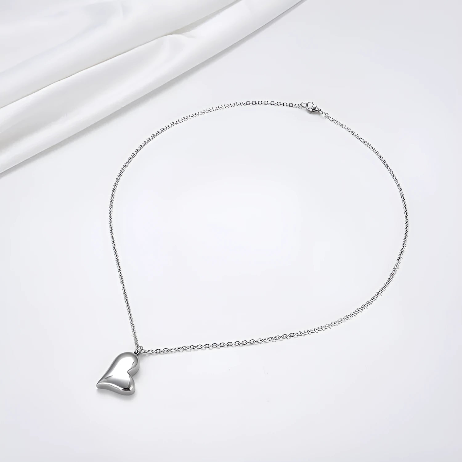 Silver coloured curved peach heart pendant necklace on a stainless steel chain with extension.