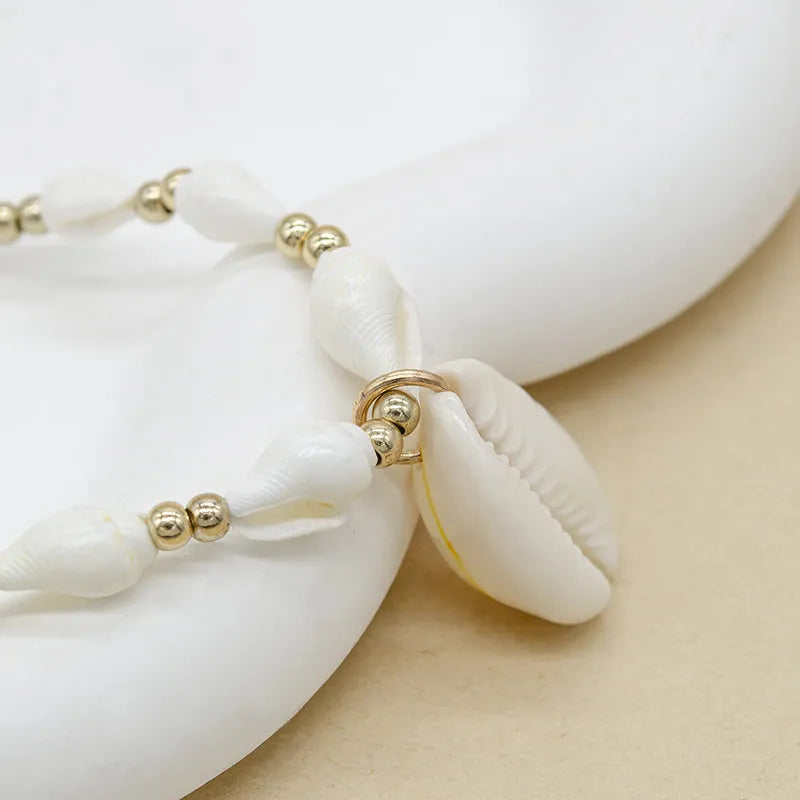 Close-up of a white conch shell necklace pendant made from Mother Pearl on a silver-toned chain.