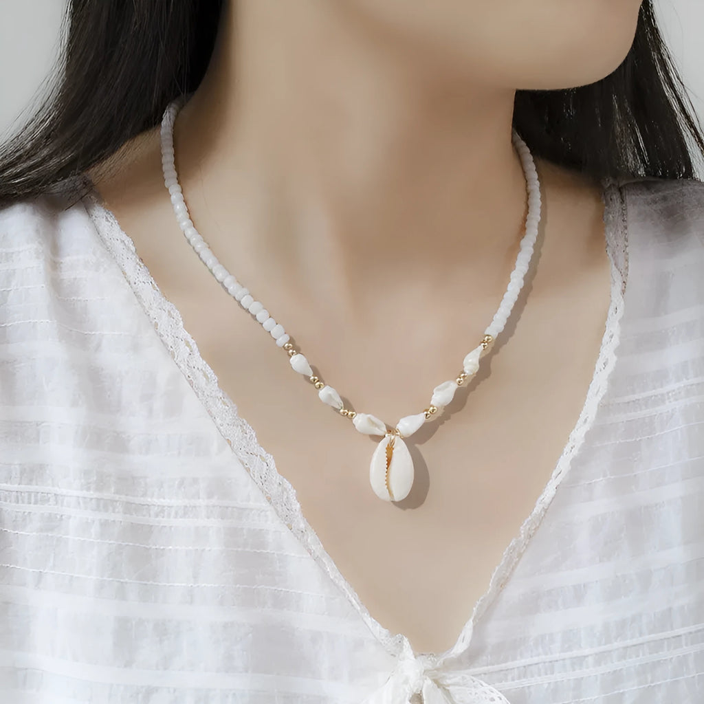 Close-up of a white conch shell necklace pendant made from Mother Pearl on a silver-toned chain.