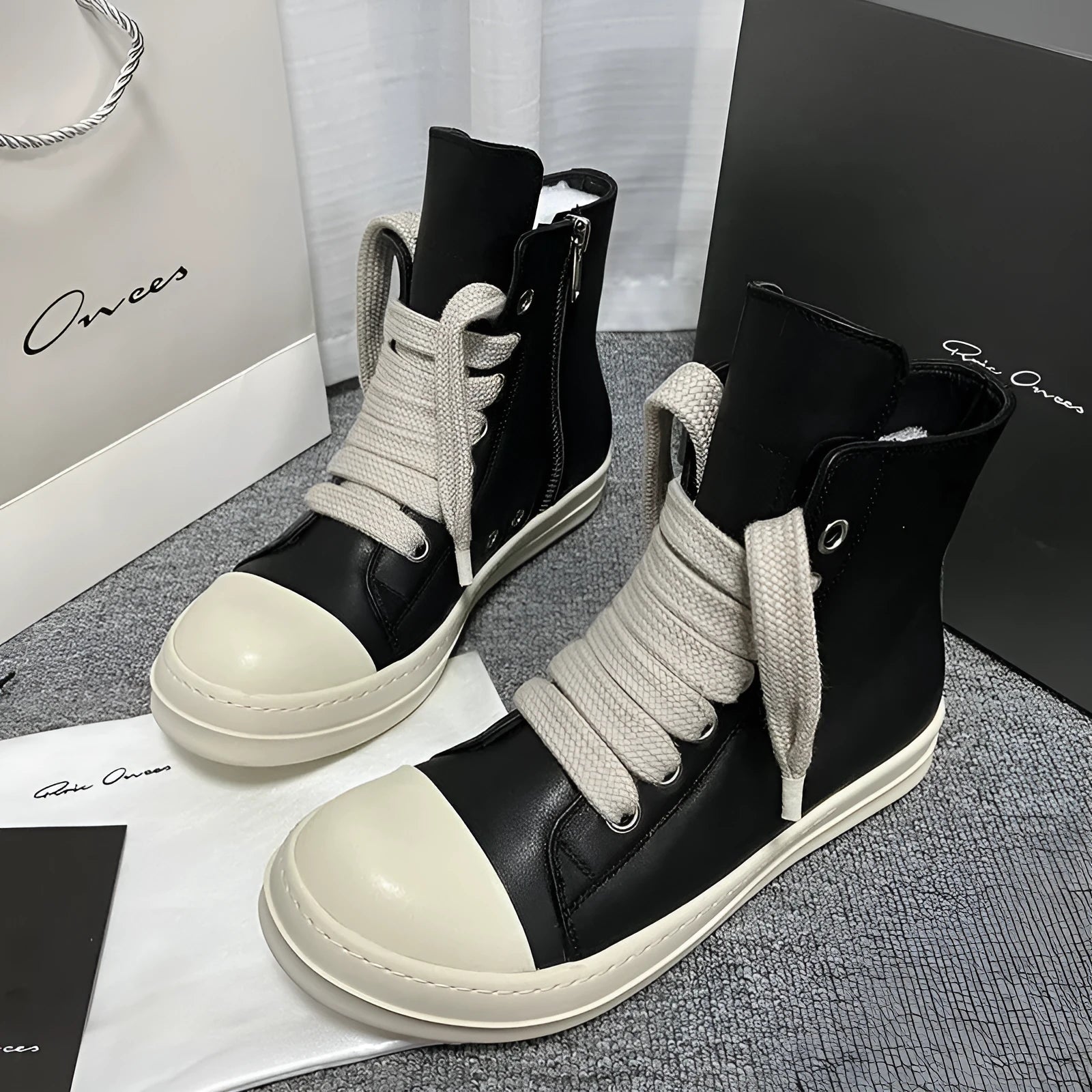 Black high-top leather sneakers with side zipper and round toe design on a white background