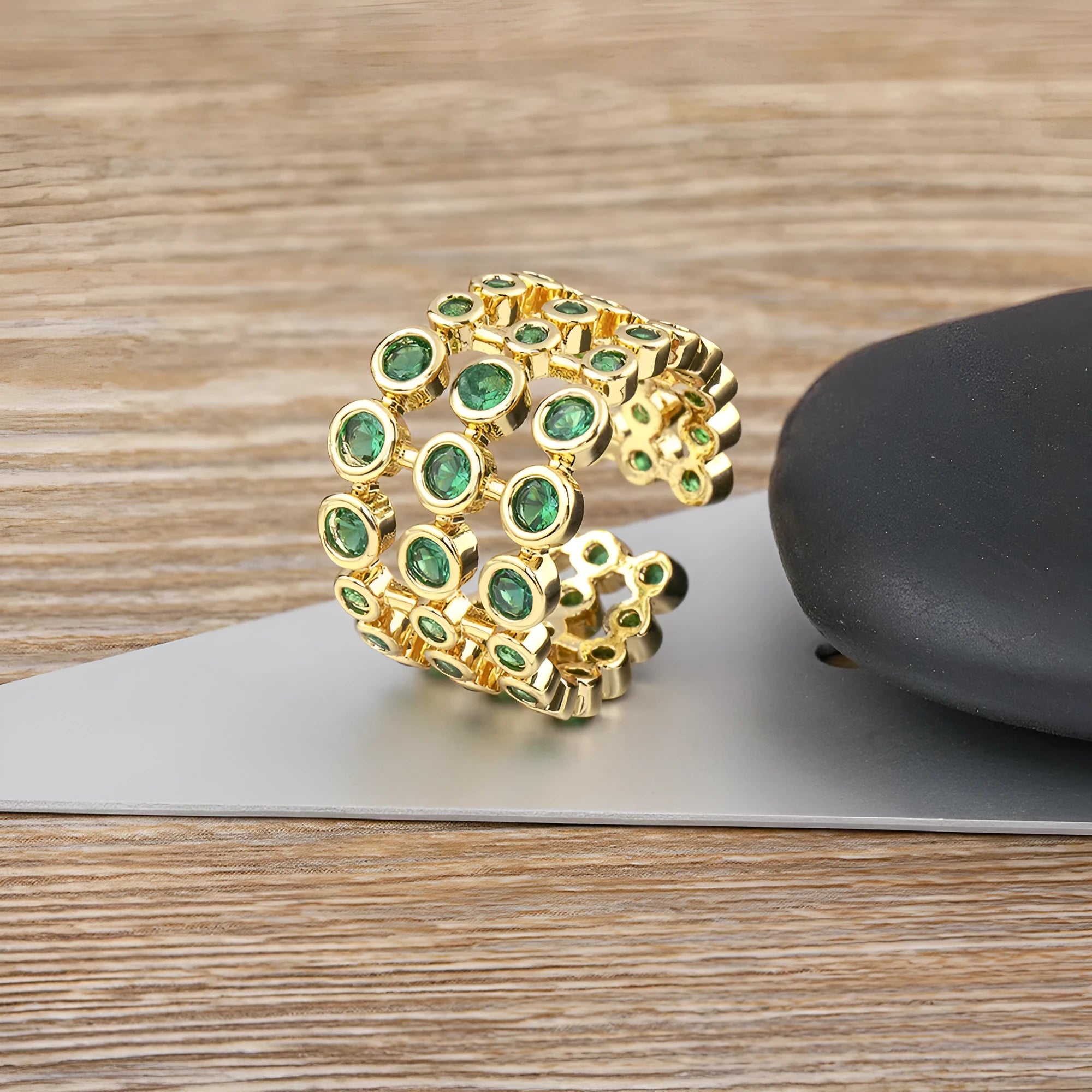 Gold-coloured wide copper ring with a large green zircon stone in a three-layer setting.