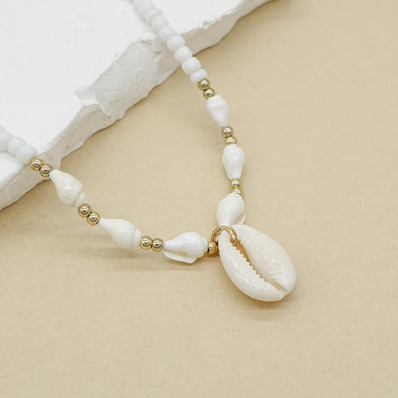 Close-up of a white conch shell necklace pendant made from Mother Pearl on a silver-toned chain.