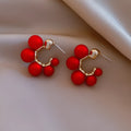 A pair of women's bell-shaped drop earrings in alloy, shown in red and white colour options.