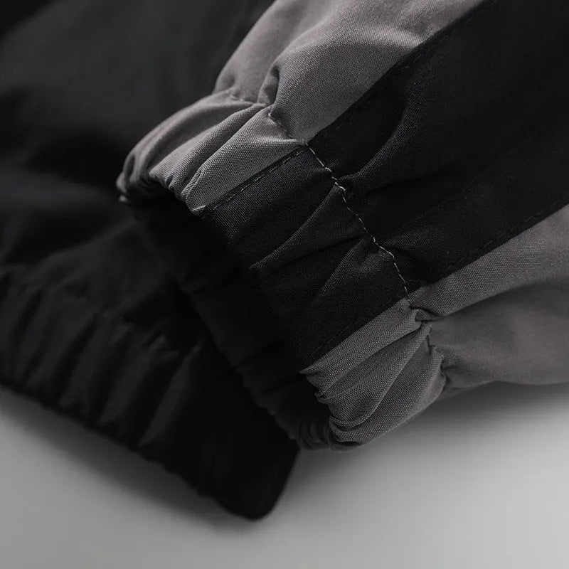 Man wearing a black casual jacket with contrasting light-coloured stitching on the seams and side pockets.