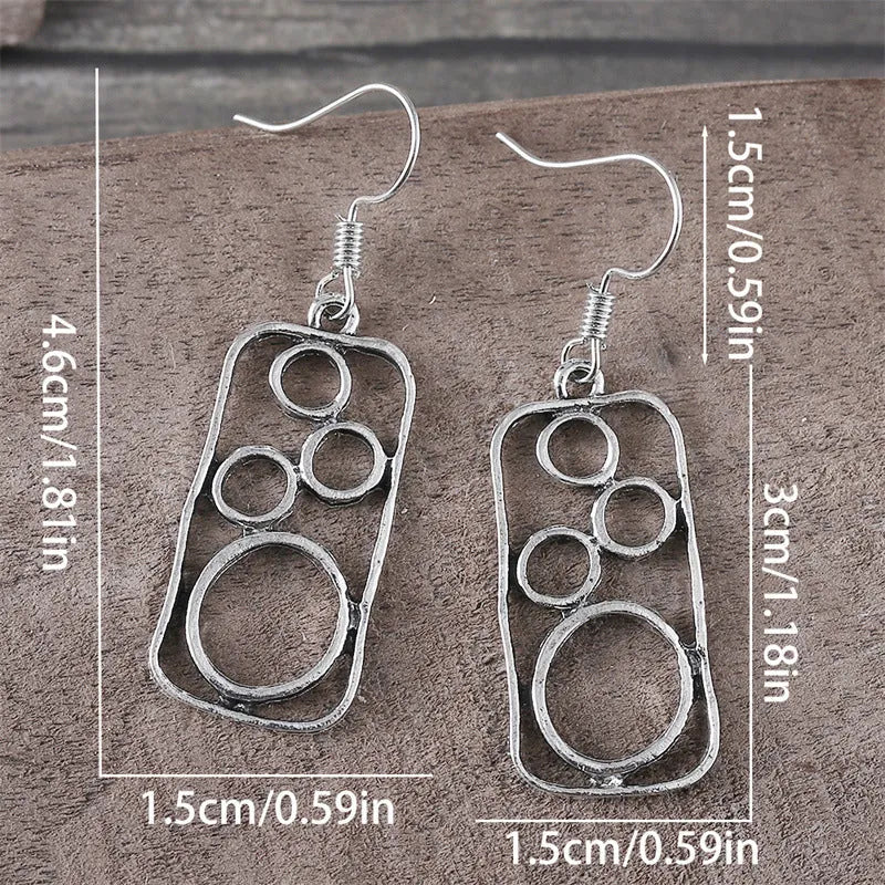 A pair of antique silver geometric earrings showing an irregular square shape inside a round ring.