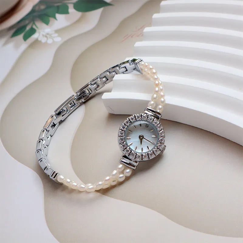 Women's light gold bracelet watch with freshwater pearls on a round 18mm dial.