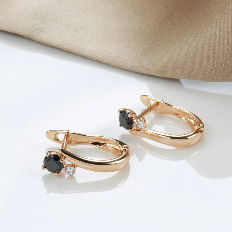 Gold geometric drop earrings with black agate stone inlay on a model's ear