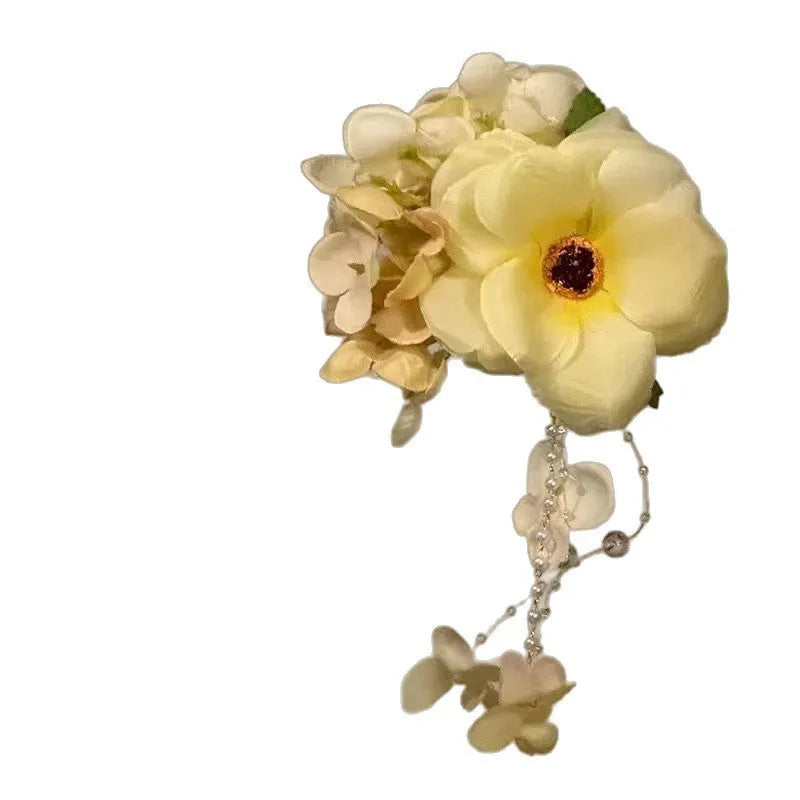 Yellow flower tassel side clip hair accessory on a white background.