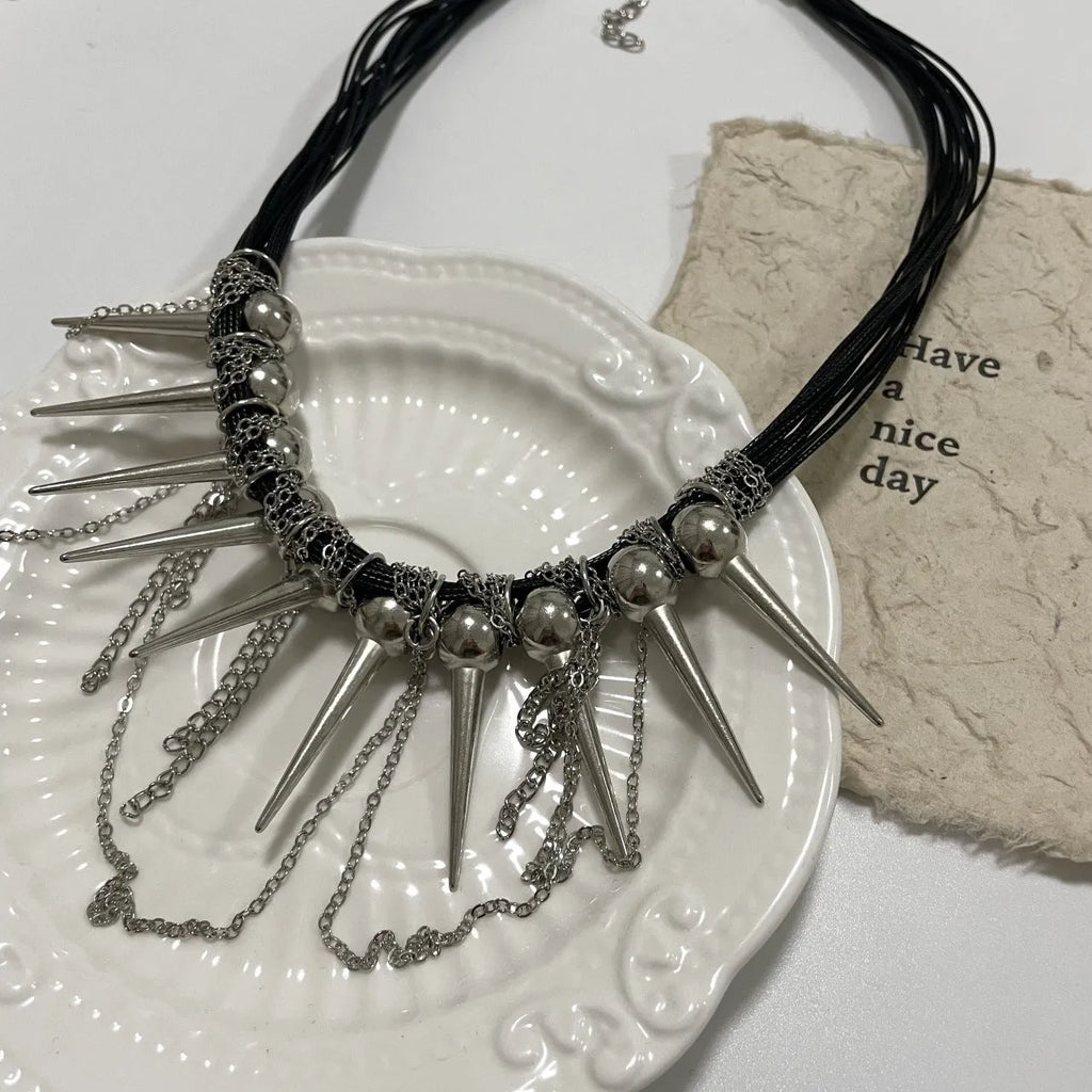 Women's leather necklace with winding beads, a tassel, and metallic point rivets.