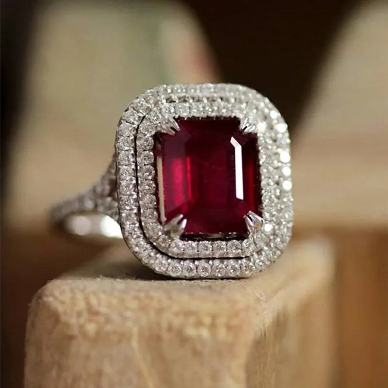 Copper square ring with red rhinestones on a woman's hand, showing geometric design.