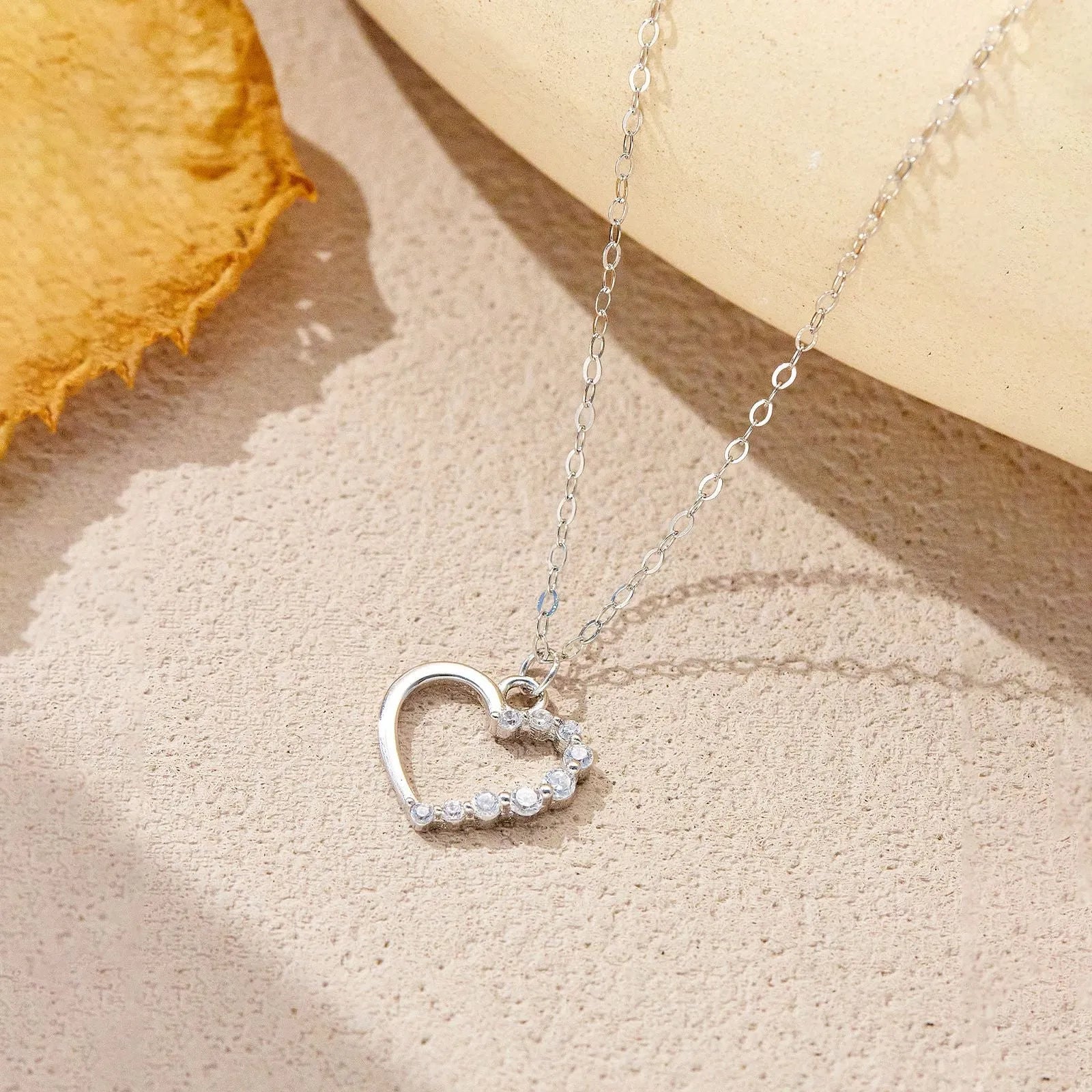 Sterling silver hollow heart pendant necklace on a regular chain, available in white gold or platinum plating.