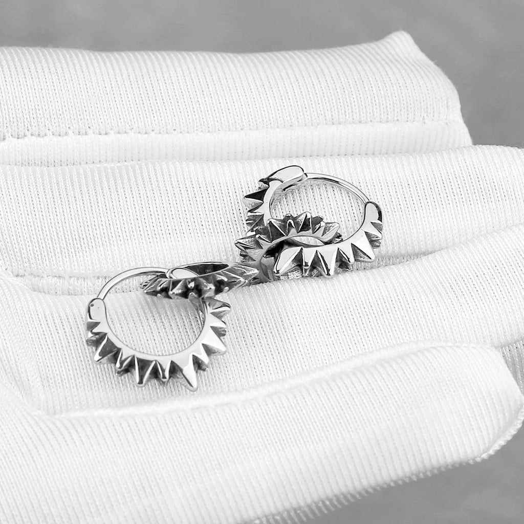 A pair of polished stainless steel round ring earrings in a retro style on a steel colour background.