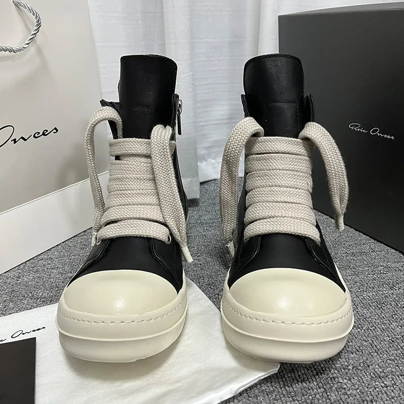 Black high-top leather sneakers with side zipper and round toe design on a white background