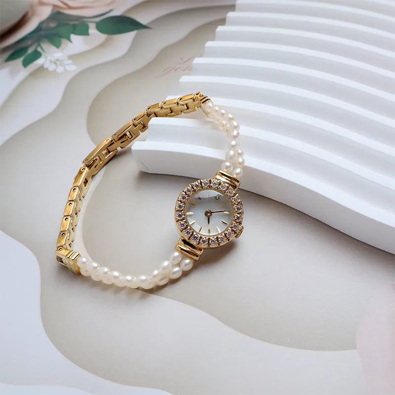 Women's light gold bracelet watch with freshwater pearls on a round 18mm dial.